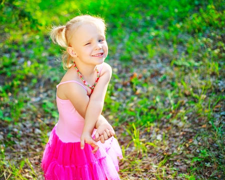 shy little girl wearing a pink dress,    in the summer parkの写真素材