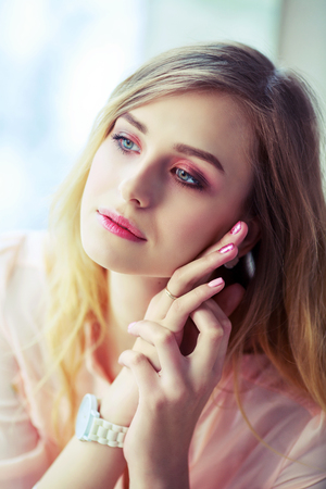 beautiful blond woman with long hair resting at home by the windowの写真素材