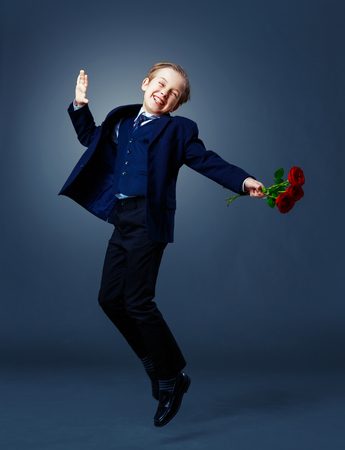 hansome boy wearing a black suit with roses in his hands, isolated against studio backgroundの写真素材