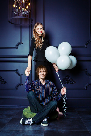 happy beautiful young couple against studio background with white balloonsの写真素材