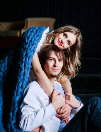 happy beautiful young couple on the stairs with a big blue blanketの写真素材