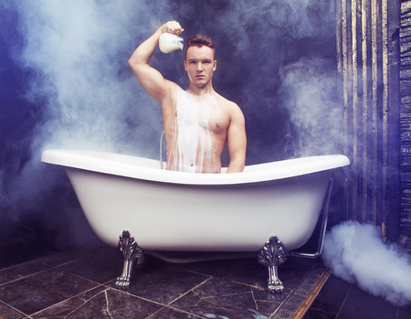 attractive muscular young man taking a bath with milkの写真素材