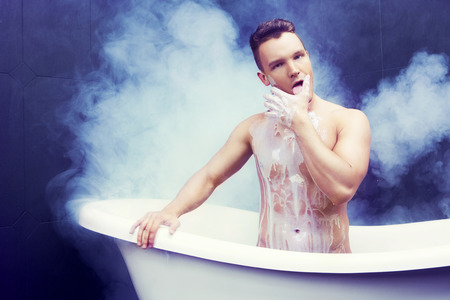 attractive muscular young man taking a bath with milkの写真素材