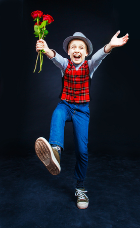 hansome boy wearing a hat and a vest with roses in his hands,  running to usの写真素材