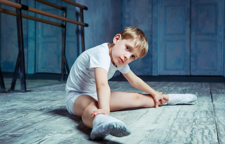 boy ballet dancer doing exercise and stretching at  dance class near the barre indoorsの写真素材