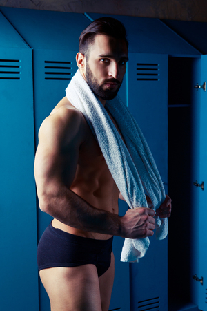 handsome muscular athletic man with a towel  in the locker room after working outの写真素材