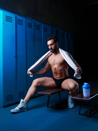 handsome muscular athletic man with a towel  in the locker room after working outの写真素材