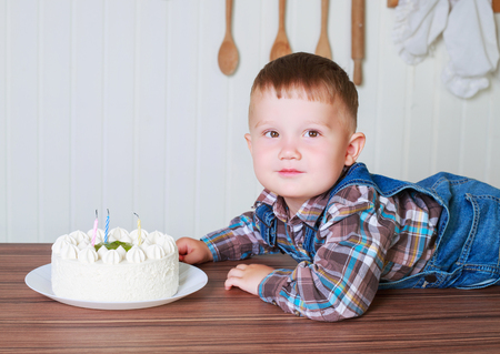 baby at home in the kitchen with a big cake with candlesの写真素材