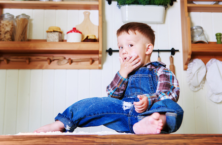 baby at home in the kitchen with dough and flour on the tableの写真素材