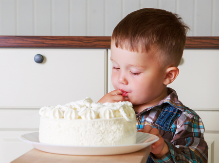 baby at home in the kitchen with a big cake with candlesの写真素材