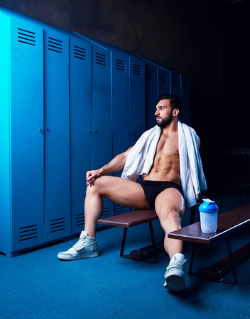 handsome muscular athletic man with a towel  in the locker room after working outの写真素材