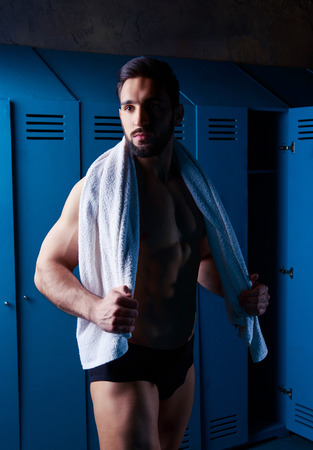 handsome muscular athletic man with a towel  in the locker room after working outの写真素材