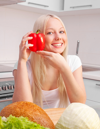 beautiful young blond woman eating at home in the kitchenの写真素材