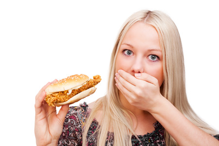 beautiful scared young blond woman with a burger, isolated against white backgroundの写真素材