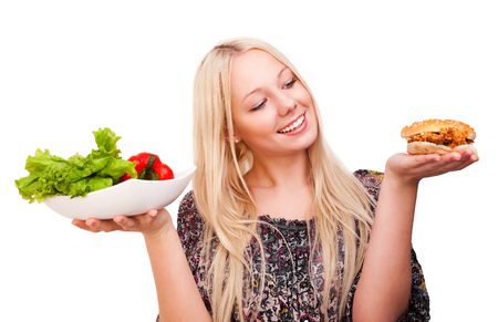 beautiful young blond woman with a burger and salad, isolated against white backgroundの写真素材