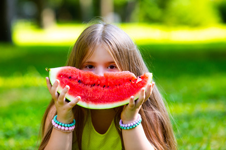 happy little girl eating watermelon outdoor in the summer parkの写真素材