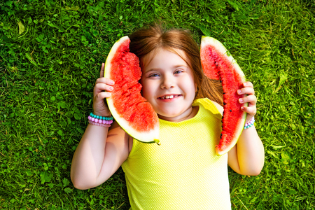 happy little girl eating watermelon outdoor in the summer parkの写真素材