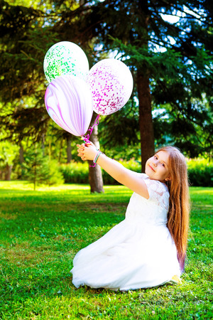 happy little girl  with many balloons  outdoor in the  summer parkの写真素材