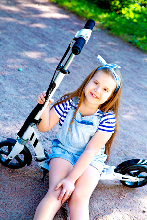 happy little girl riding a scooter outdoor in the  summer parkの写真素材