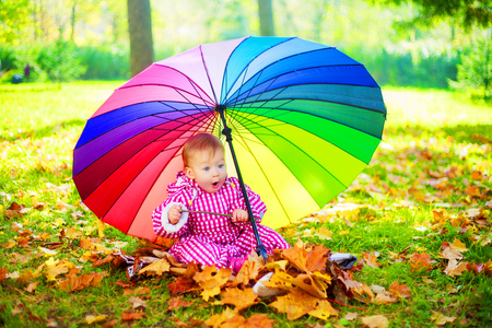 happy baby girl  with a big umbrella in the autumn parkの写真素材