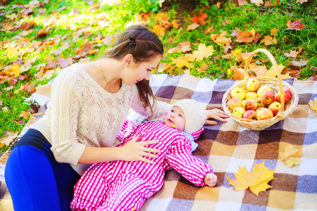 happy mother and baby having picnic in the autumn parkの写真素材