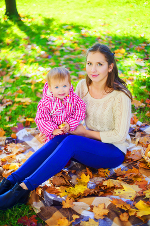 happy mother and baby resting in the autumn parkの写真素材