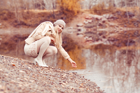 happy blond woman walking alone in the autumn parkの写真素材