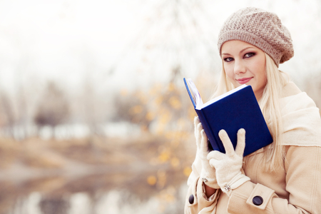 happy blond woman reading a book  in the autumn parkの写真素材