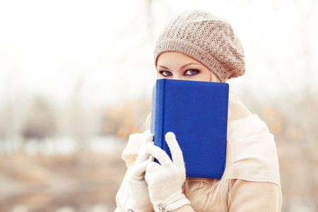 happy blond woman reading a book  in the autumn parkの写真素材