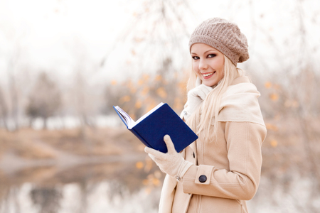 happy blond woman reading a book  in the autumn parkの写真素材