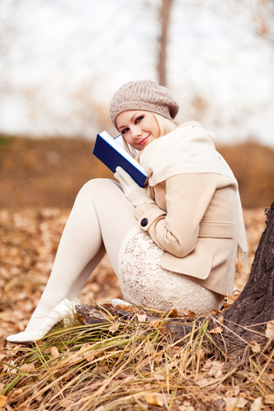 happy blond woman reading a book  in the autumn parkの写真素材