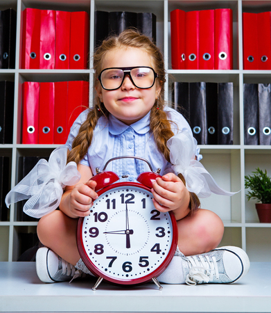 cute little girl wearing glasses with   a clockの写真素材