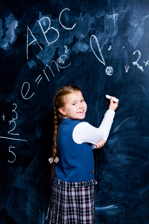 happy  little girl   at school against chalkboardの写真素材