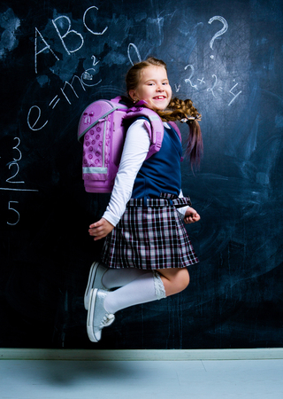 happy  little girl   at school against chalkboardの写真素材