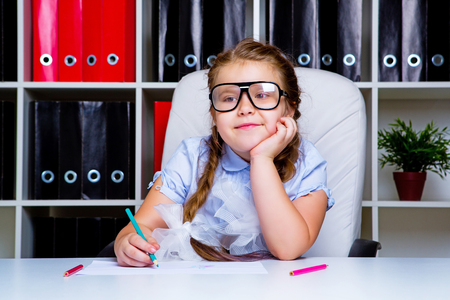 cute little girl wearing glasses doing homeworkの写真素材
