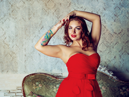 beautiful young woman with rose tatoo, wearing a red dressの写真素材
