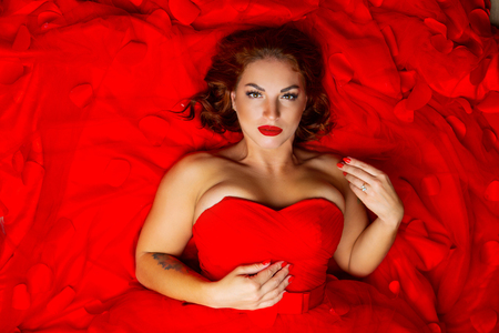 beautiful young woman with rose tatoo, wearing a red dressの写真素材