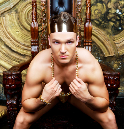 striptease dancer wearing costume with a golden crown in the studio against golden studio backgroundの写真素材
