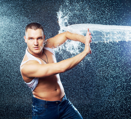 attractive young man with wet clothes  with a splash of water, studio photoshootの写真素材