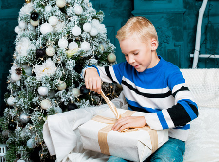 happy boy  at home with a Christmas tree and a presentの写真素材