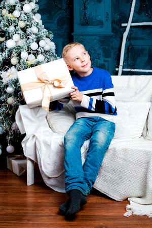 happy boy  at home with a Christmas tree and a presentの写真素材