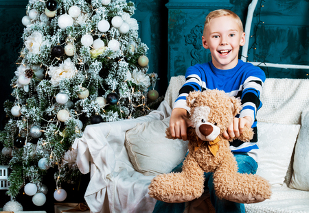 happy boy  at home with a Christmas tree and a presentの写真素材