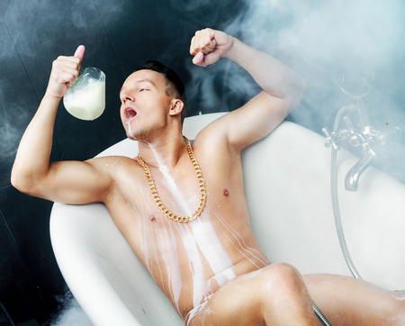 attractive muscular young man taking a bath with milkの写真素材