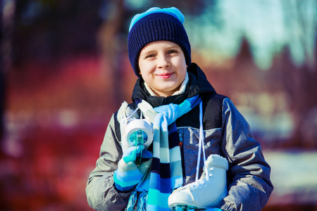 happy cute boy going ice skating outdoor in the winter parkの写真素材