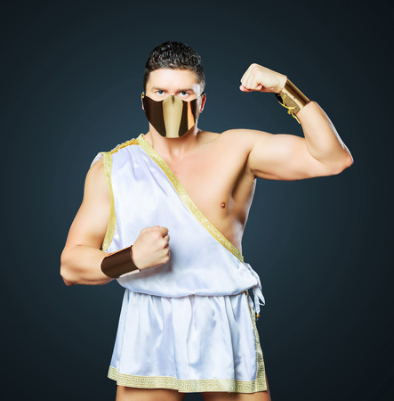 striptease dancers wearing costume of a gladiator against dark studio backgroundの写真素材