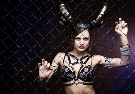 beautiful dancer wearing leather and horns, against drid fenceの写真素材