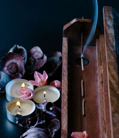 incense stick aroma with smoke in a wooden holder with dried petalsの写真素材