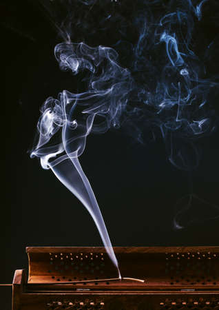 incense stick aroma with smoke in a wooden handmade holder isolated on backgroundの写真素材
