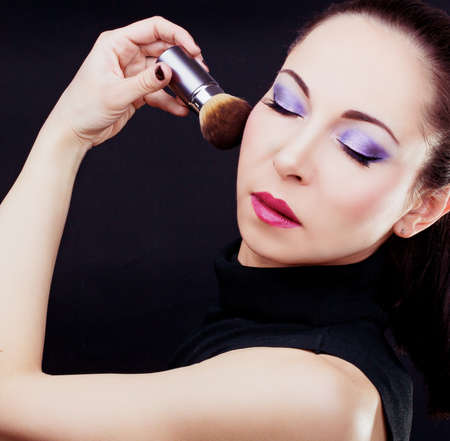 Portrait of young beautiful woman holding the makeup brushの写真素材