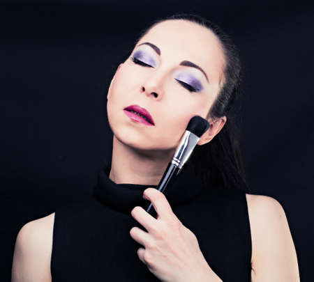 Portrait of young beautiful woman holding the makeup brushの写真素材